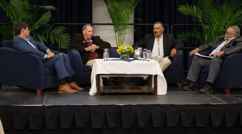 Four men sitting together on stage