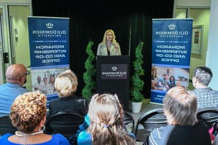 A woman stands at a podium during an opening event.